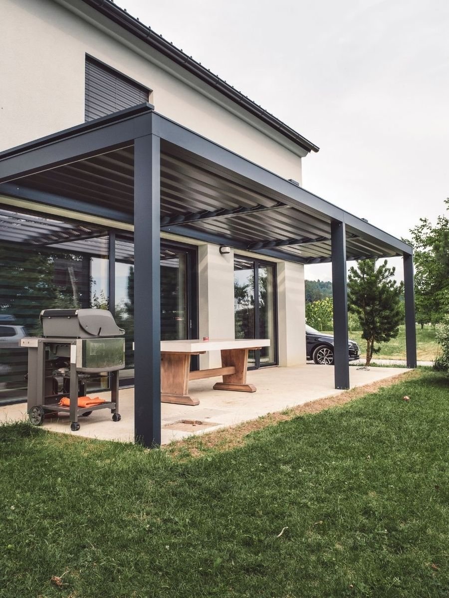 Pergola en aluminium adossée à une maison, au-dessus d'une terrasse